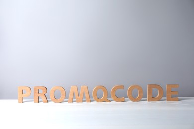 Photo of Words Promo Code made of wooden letters on white table, space for text