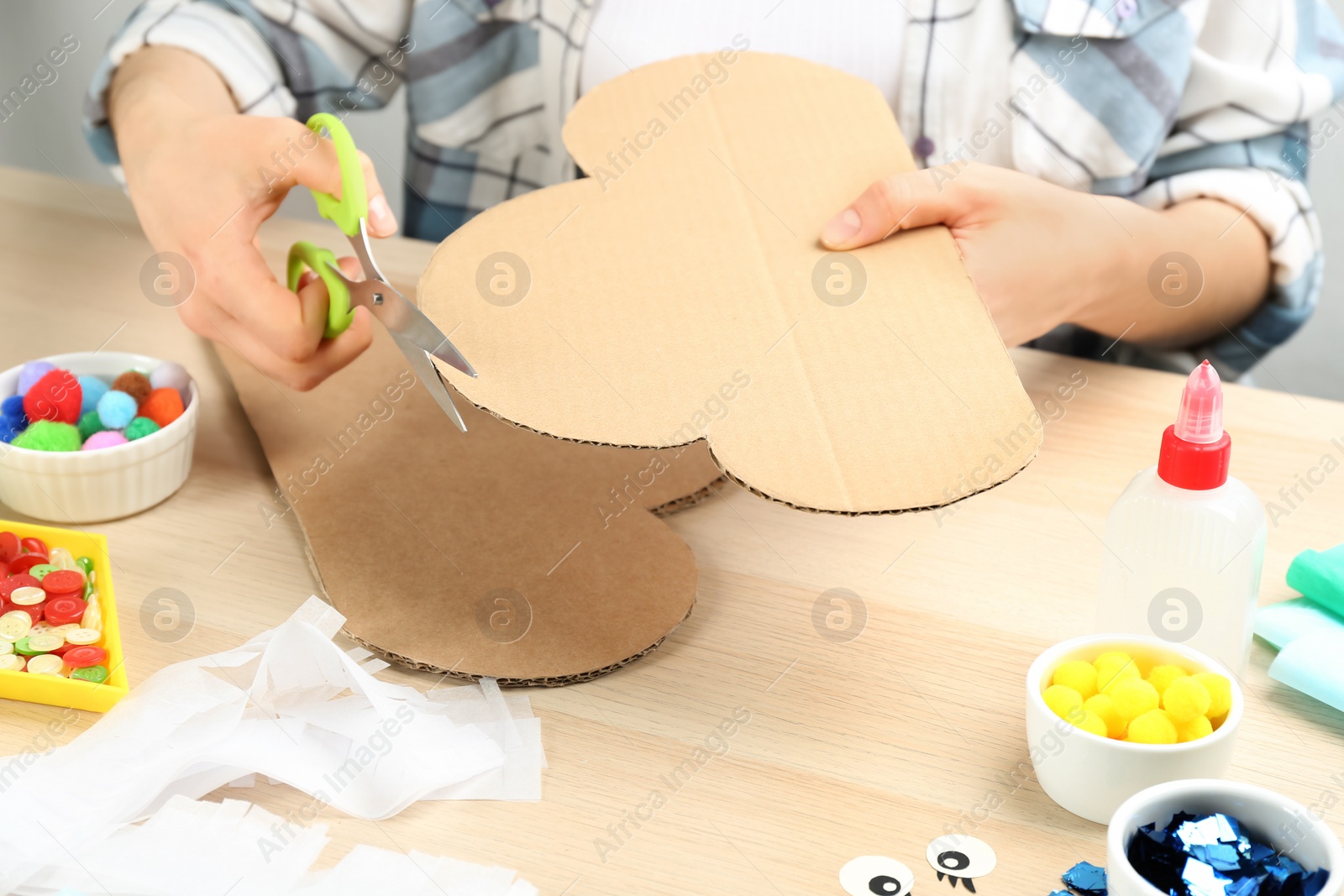 Photo of Woman making cardboard cloud at wooden table, closeup. Pinata diy