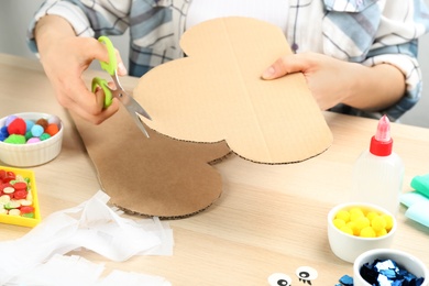 Woman making cardboard cloud at wooden table, closeup. Pinata diy