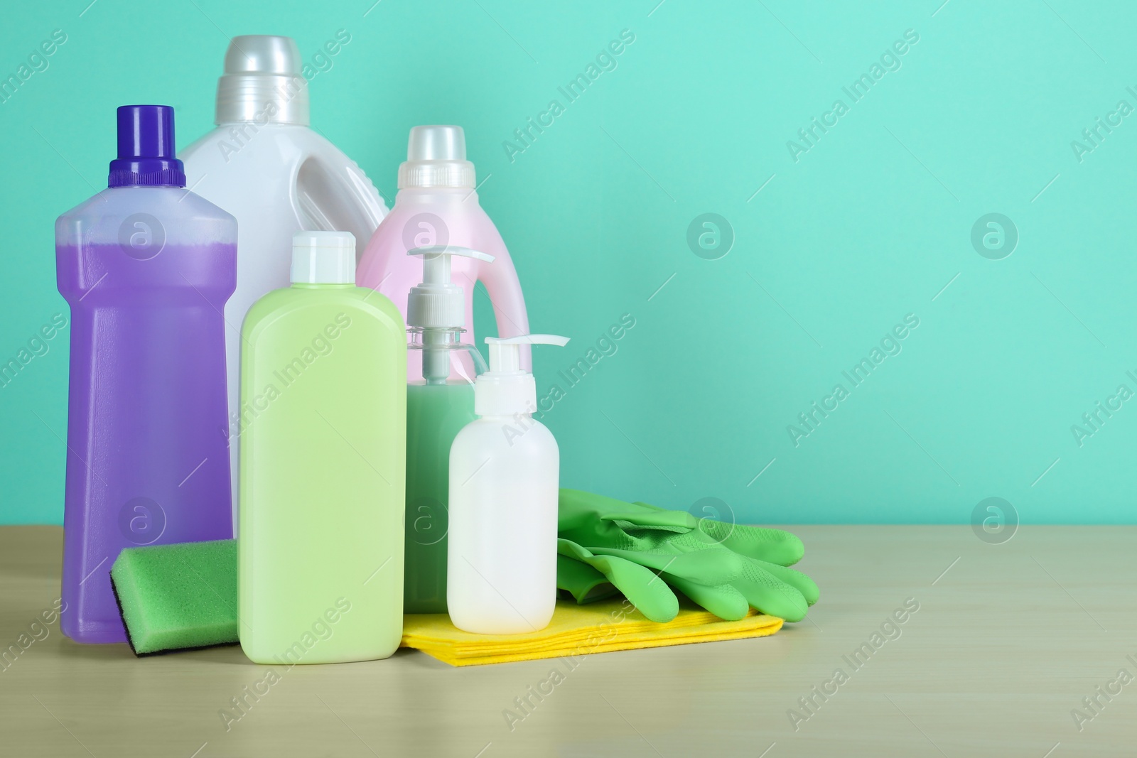 Photo of Different cleaning supplies and tools on table against turquoise background, space for text