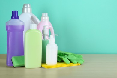 Photo of Different cleaning supplies and tools on table against turquoise background, space for text