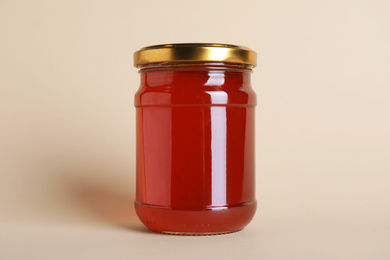 Photo of Jar of organic honey on beige background