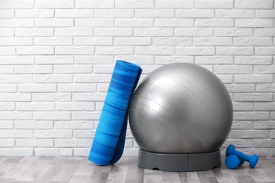 Photo of Set of fitness equipment on floor near brick wall. Space for text