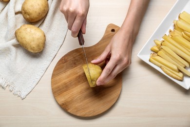 Photo of Woman cut potatoes at white wooden table, top view