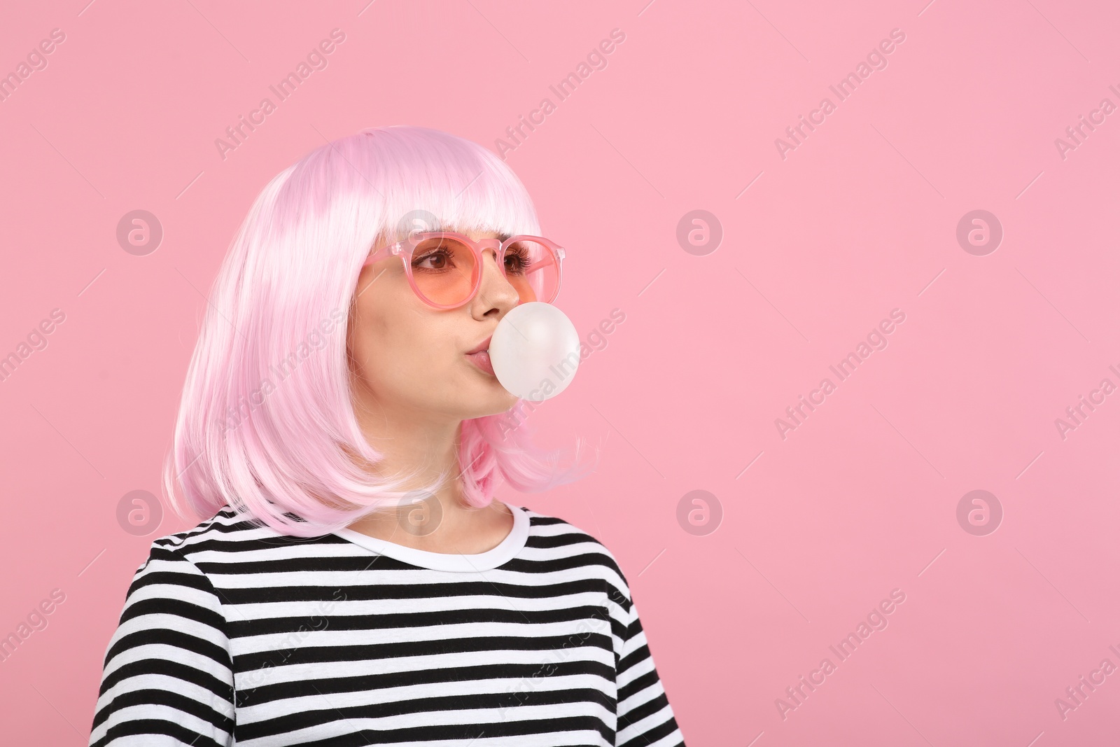 Photo of Beautiful woman in sunglasses blowing bubble gum on pink background, space for text