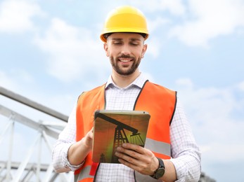 Image of Professional engineer wearing uniform with tablet outdoors