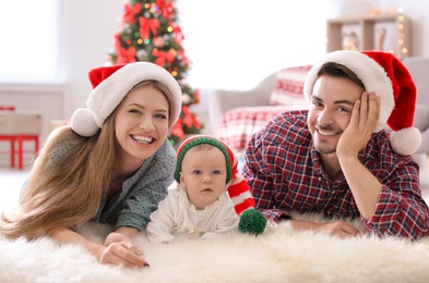 Happy couple with baby in Christmas hats at home