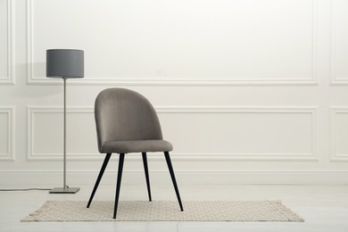 Photo of Modern beige chair and floor lamp near white wall indoors. Space for text