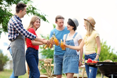 Photo of Young people having barbecue with modern grill outdoors