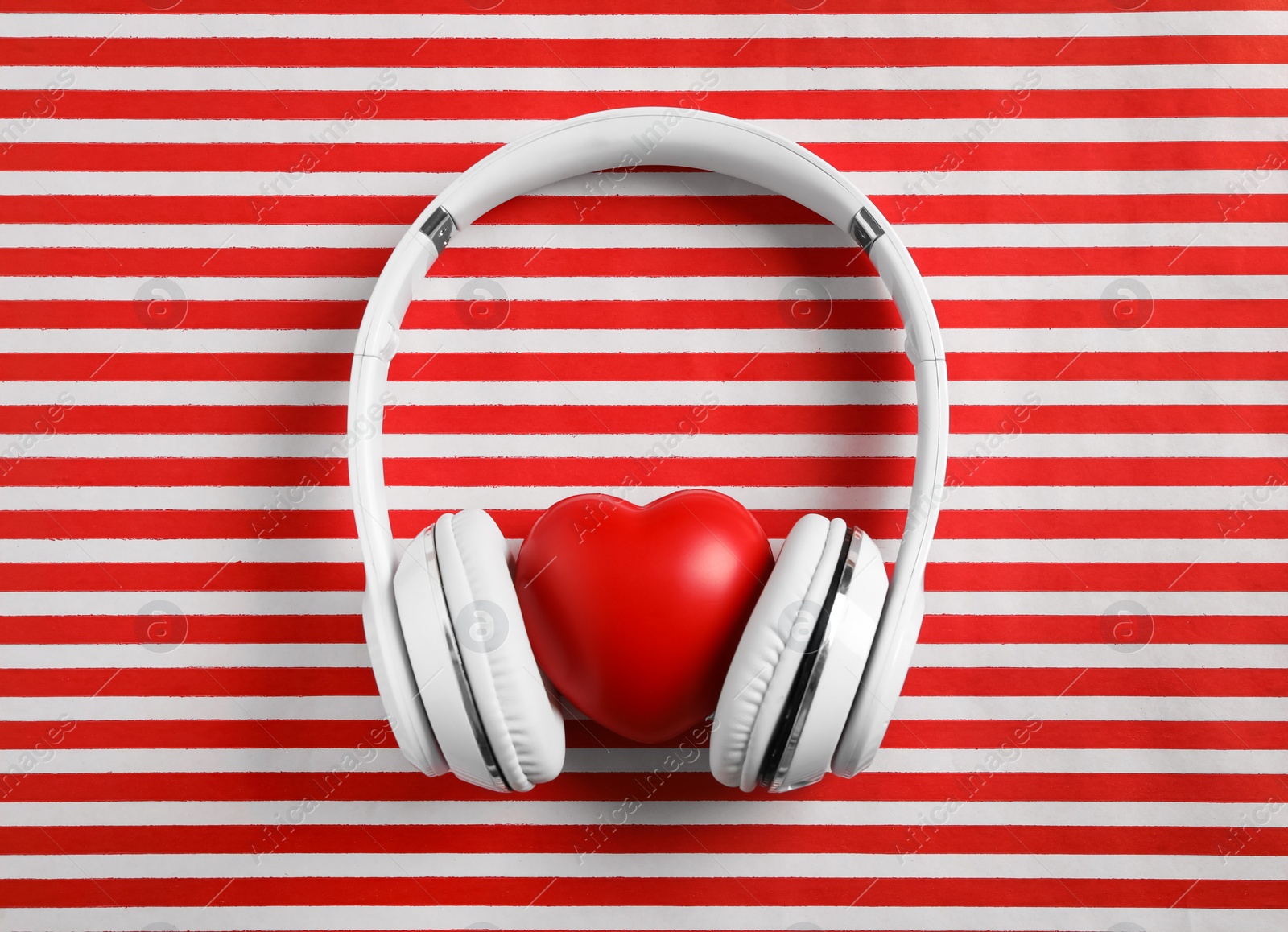 Photo of Modern headphones and red heart on color background, flat lay. Listening love music songs