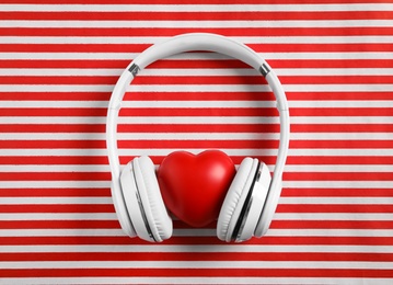 Photo of Modern headphones and red heart on color background, flat lay. Listening love music songs