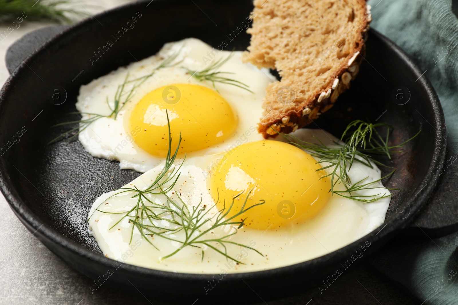 Photo of Delicious fried eggs served with bread on grey table, closeup