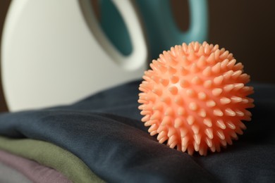Photo of Orange dryer ball on stacked clean clothes, closeup