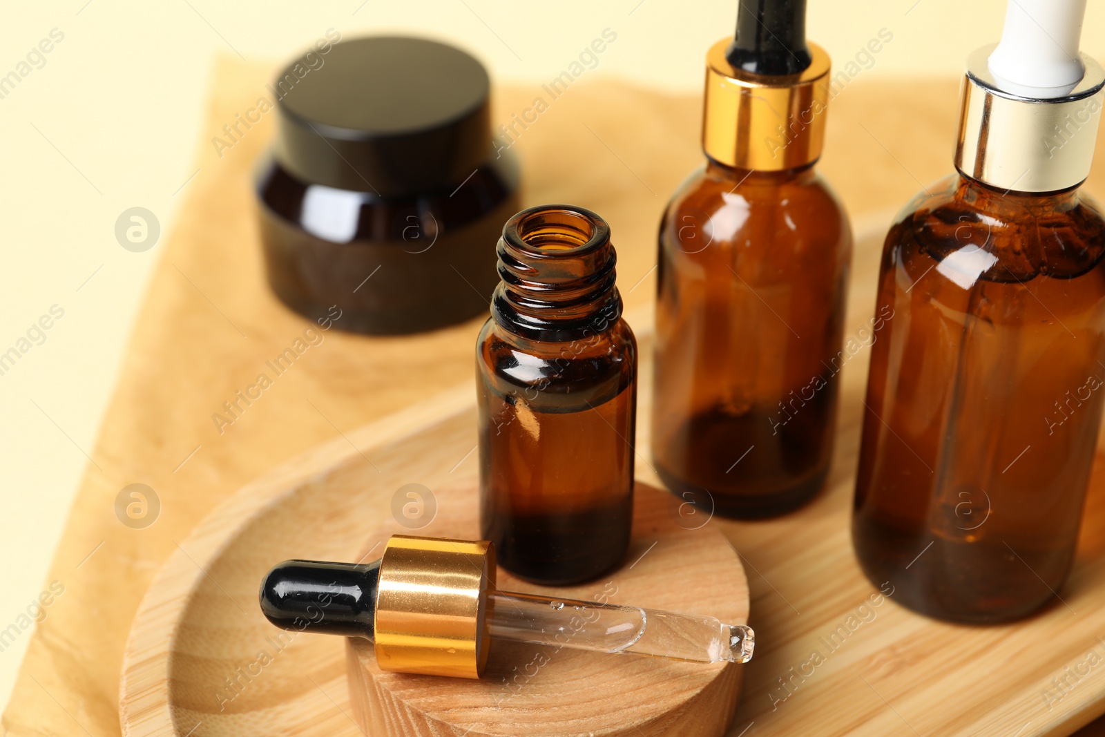 Photo of Composition with bottles of cosmetic serum on beige background, closeup