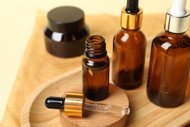 Composition with bottles of cosmetic serum on beige background, closeup