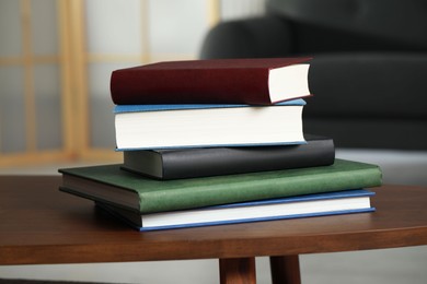 Photo of Stack of hardcover books on wooden coffee table indoors
