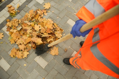 Photo of Street cleaner sweeping fallen leaves outdoors on autumn day, closeup
