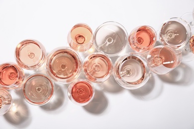 Different glasses with rose wine on white background, top view