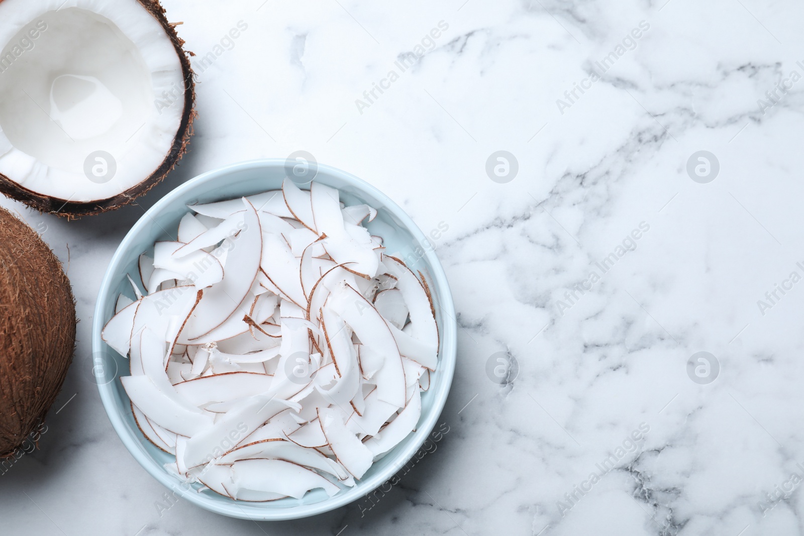 Photo of Flat lay composition with fresh coconut flakes on white marble table. Space for text