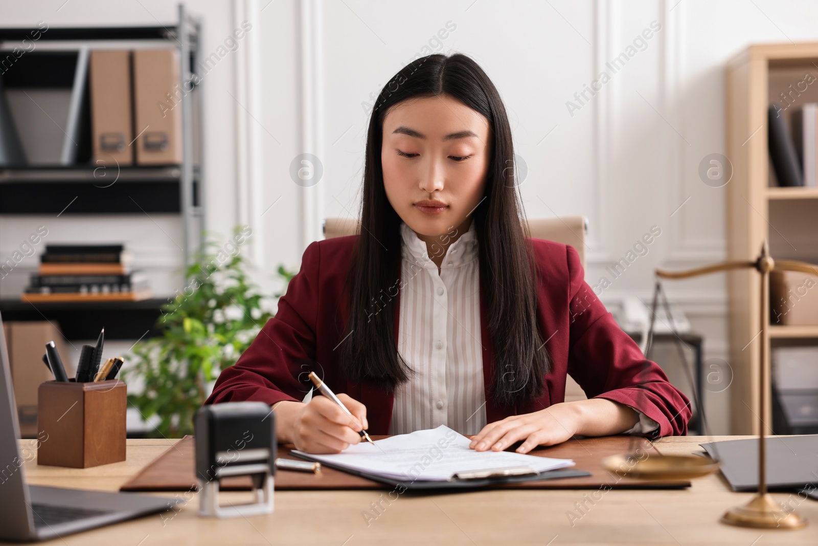 Photo of Notary signing document at table in office