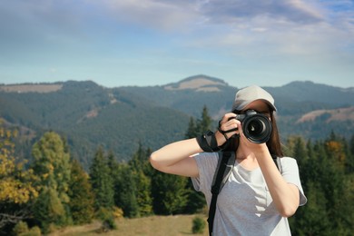 Professional photographer taking picture with modern camera in mountains. Space for text