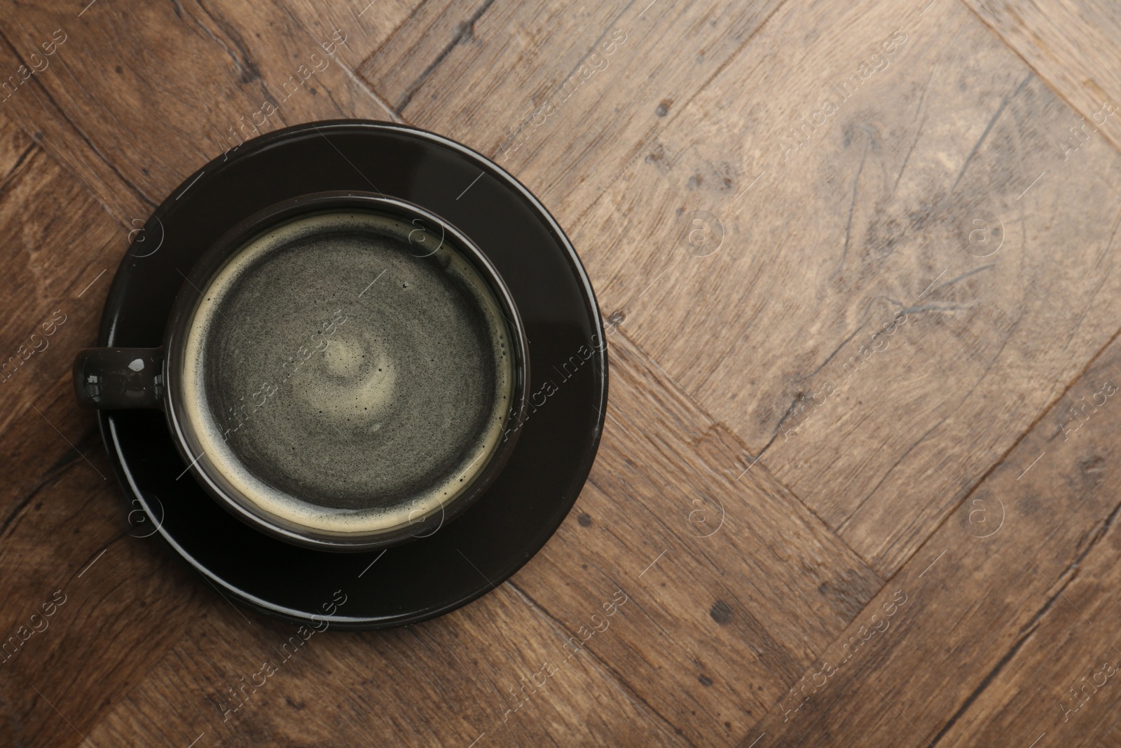 Photo of Hot coffee in cup on wooden table, top view. Space for text