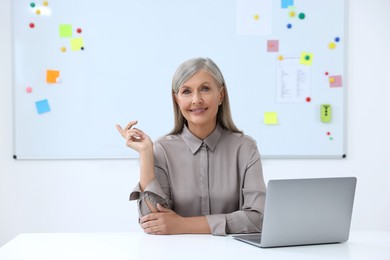 Photo of Professor giving lecture near laptop at desk in classroom