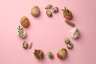 Photo of Frame made of festively decorated eggs and natural decor on pink background, top view with space for text. Happy Easter