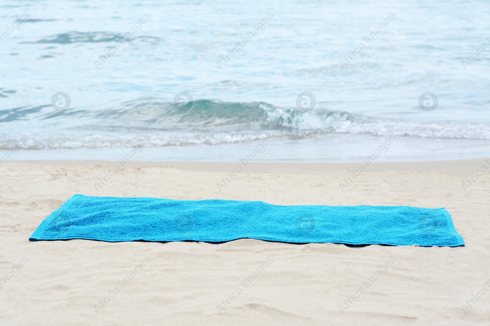 Photo of Blue towel on sandy beach near sea