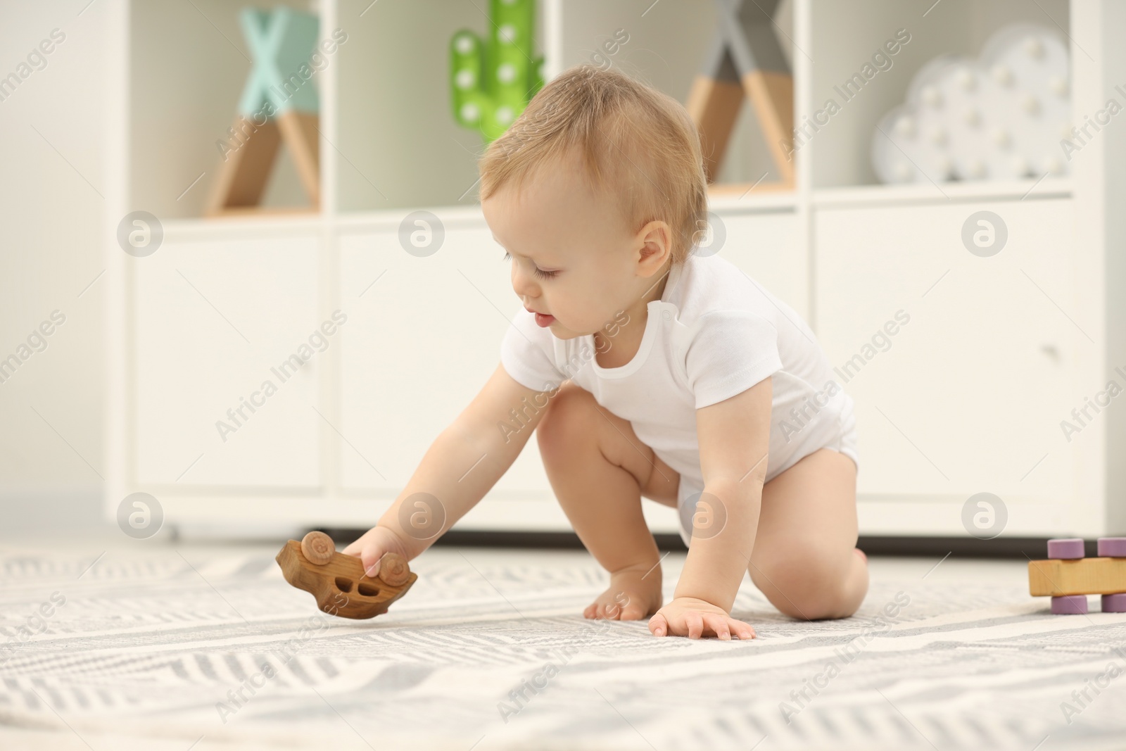 Photo of Children toys. Cute little boy playing with wooden car on rug at home