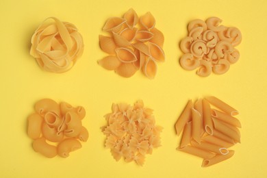 Different types of pasta on yellow background, flat lay