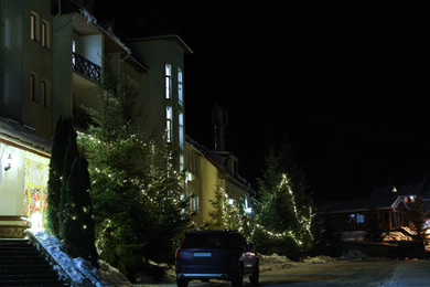 Modern car on snowy road near hotel at night. Winter vacation