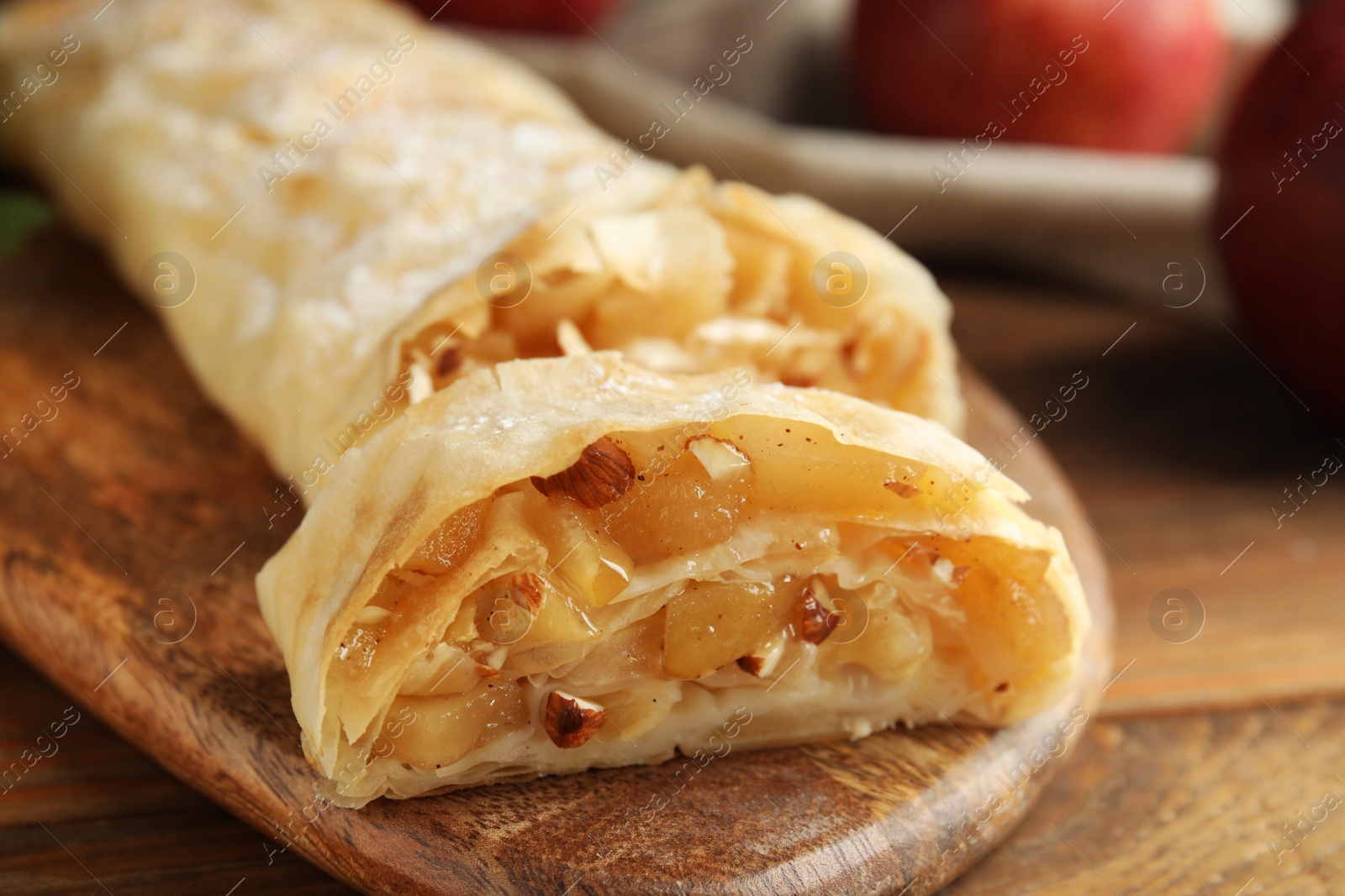 Photo of Delicious apple strudel with almonds on wooden table, closeup