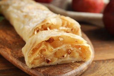 Photo of Delicious apple strudel with almonds on wooden table, closeup