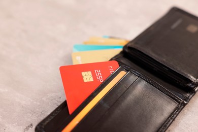 Photo of Many different credit cards and leather wallet on grey table, closeup