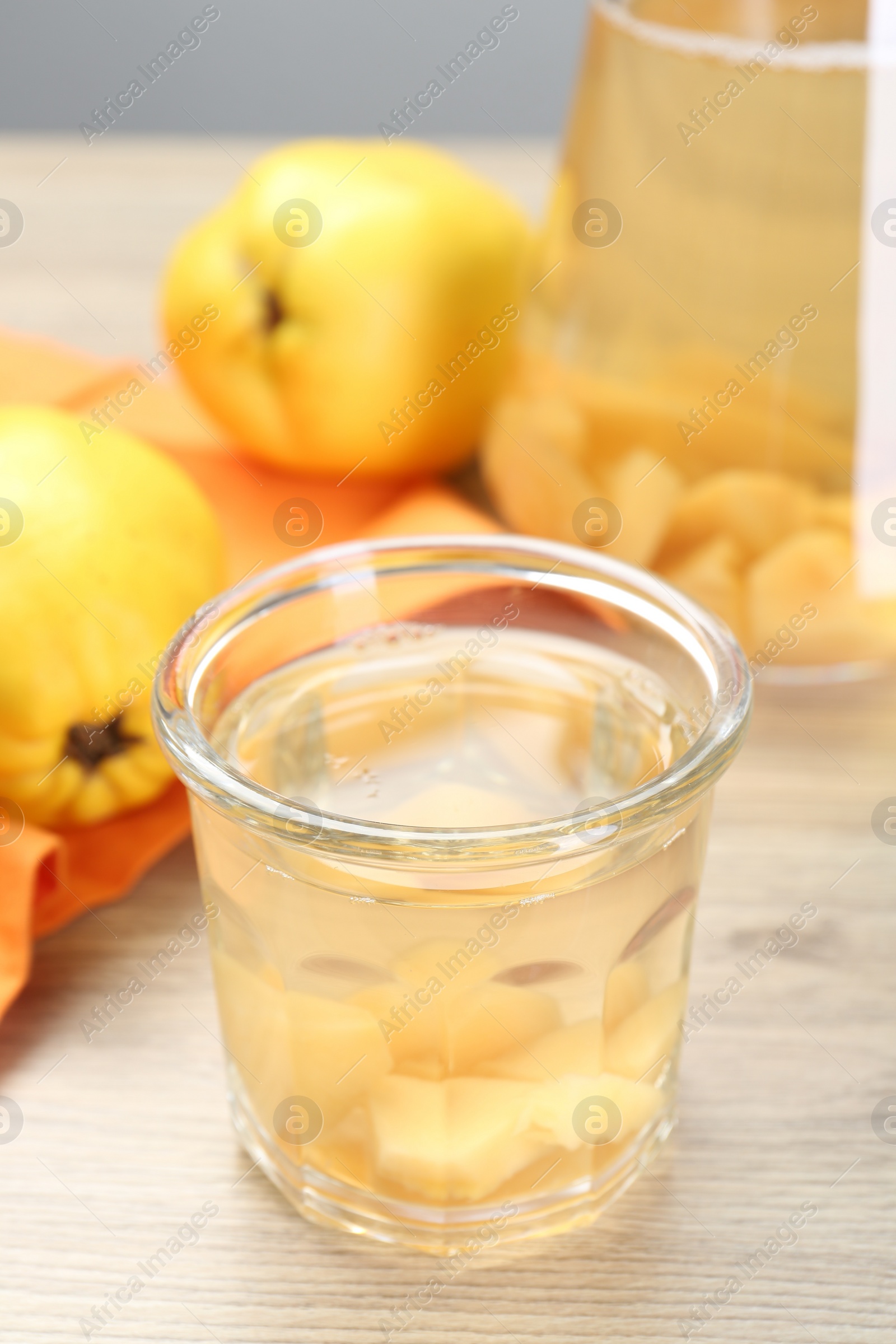 Photo of Delicious quince drink in glass and fresh fruits on wooden table