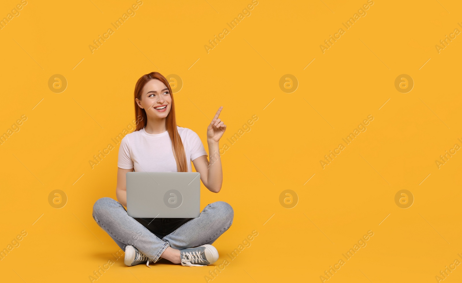 Photo of Smiling young woman with laptop on yellow background, space for text