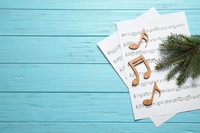 Photo of Christmas tree branch, notes and music sheets on blue wooden table, flat lay with space for text