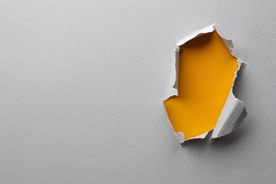 Photo of Hole in white paper on yellow background, space for text