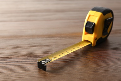 Photo of Metal measuring tape on wooden background. Space for text