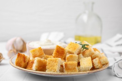 Photo of Delicious crispy croutons with rosemary on white table, closeup