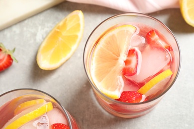 Tasty refreshing drink with strawberries and lemon on light grey table, above view