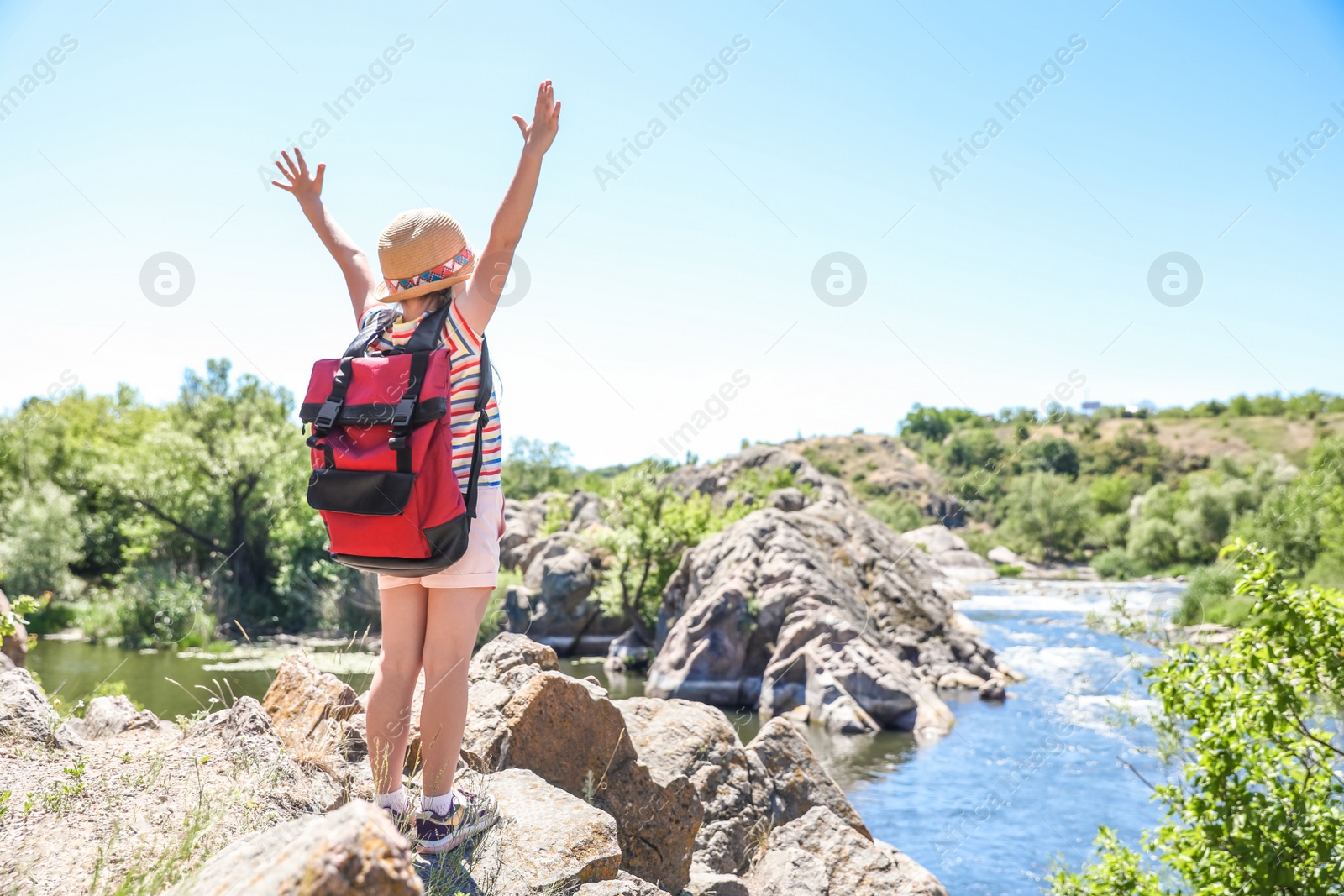 Photo of Little girl on rock near river. Summer camp