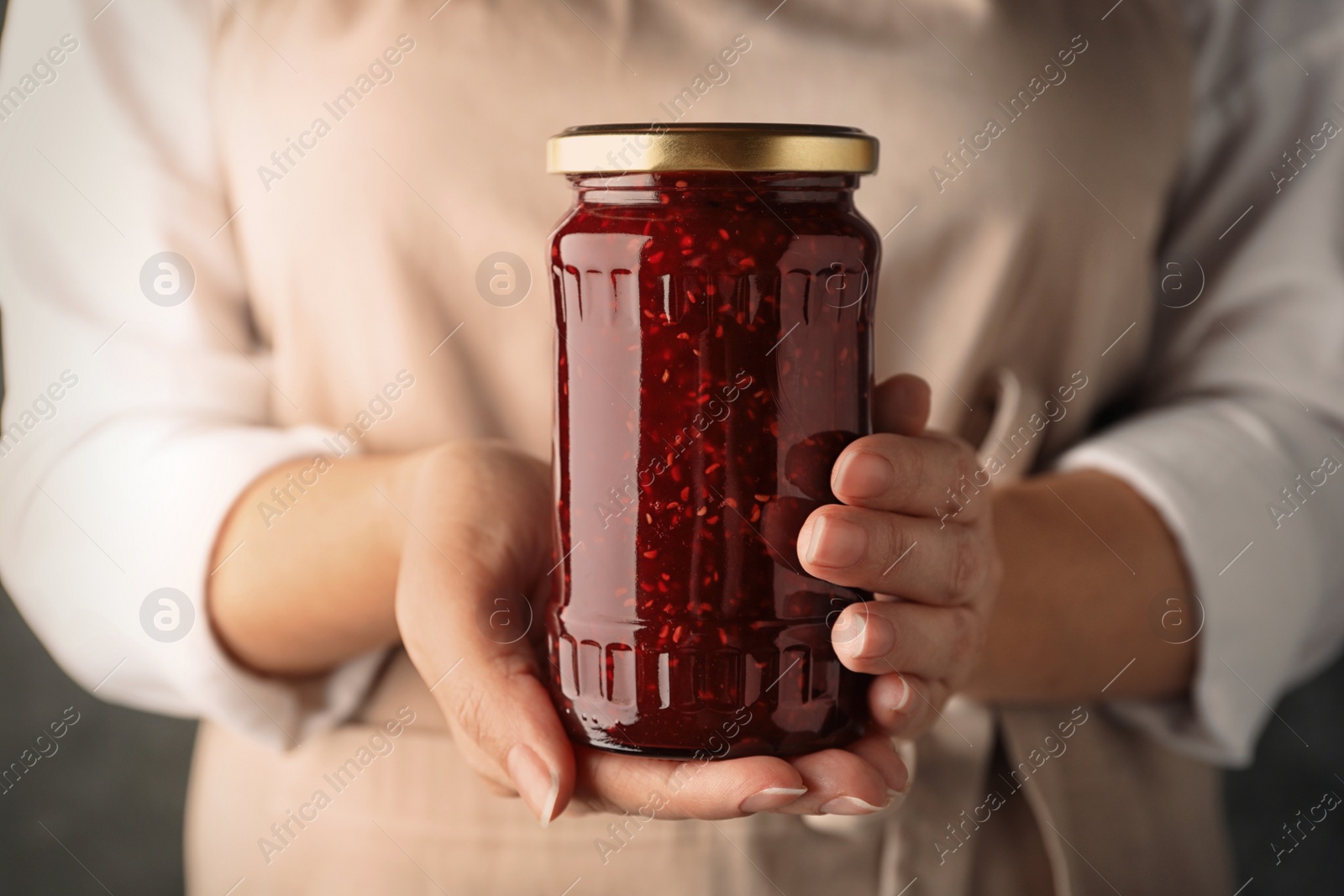 Photo of Woman with jar of raspberry jam, closeup