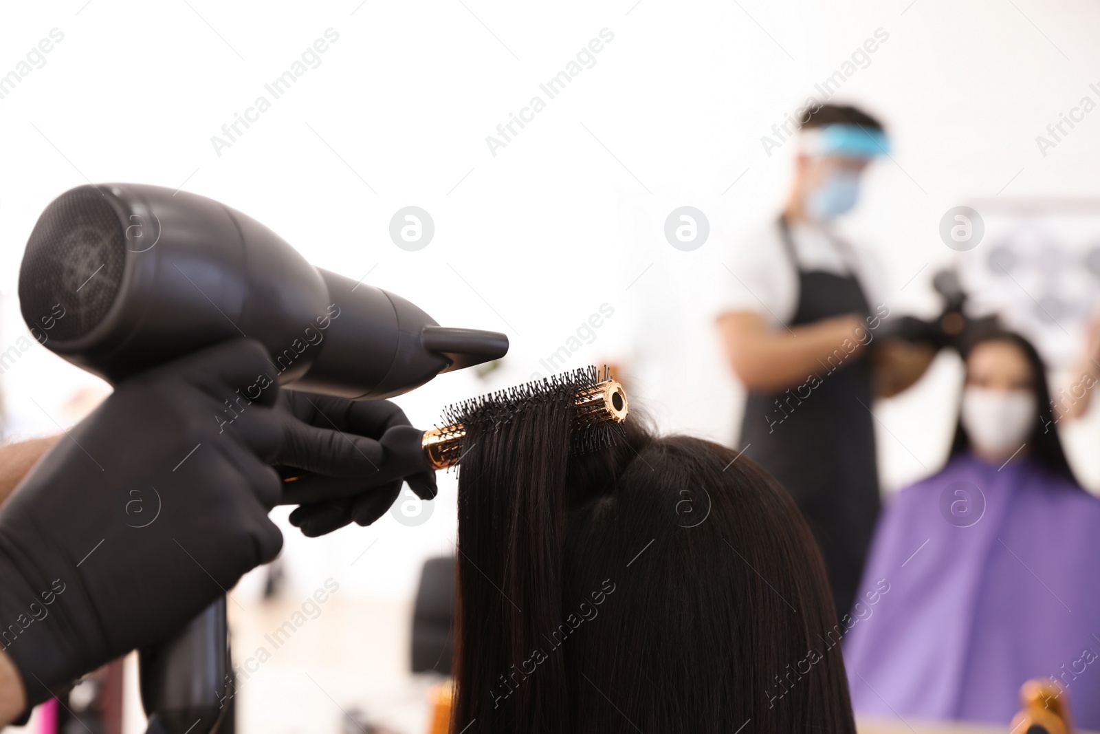 Photo of Professional stylist working with client in salon, closeup. Hairdressing services during Coronavirus quarantine