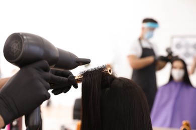 Professional stylist working with client in salon, closeup. Hairdressing services during Coronavirus quarantine