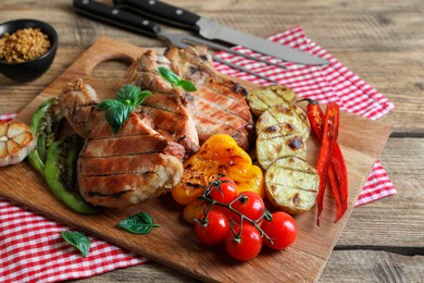 Photo of Delicious grilled meat and vegetables served on wooden table, closeup