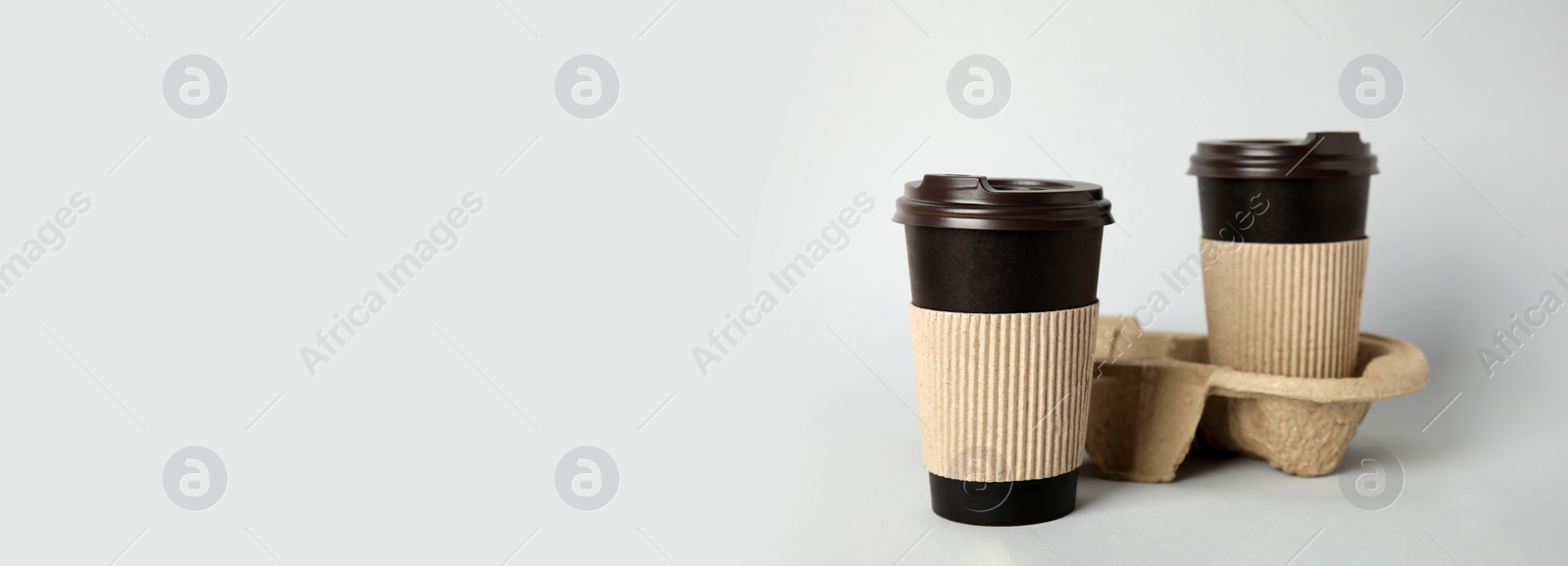 Image of Takeaway paper coffee cups with sleeves, plastic lids and cardboard holder on light grey background, space for text. Banner design