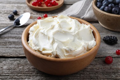 Photo of Tasty cream cheese and fresh berries on wooden table