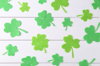 St. Patrick's day. Decorative green clover leaves on white wooden table, flat lay